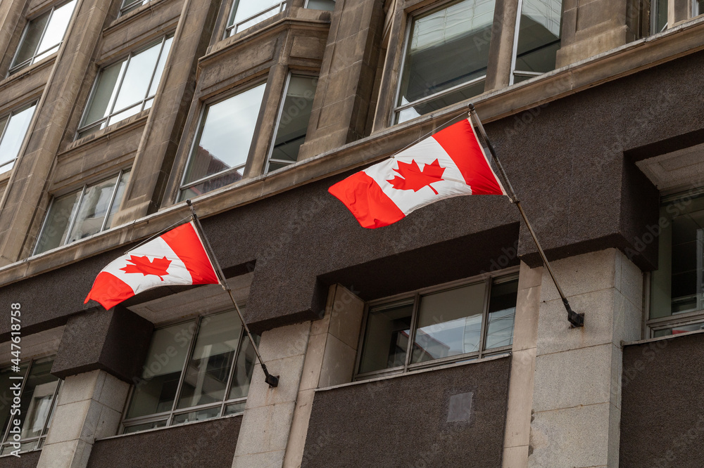 Naklejka premium Canadian flags waving in the wind, attached to building in downtown of Ottawa city in Canada.