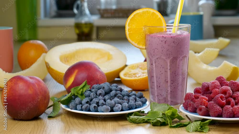 Melon, raspberry and blueberry smoothie in a glass on the background of fresh fruits and berries Melon, raspberry and blueberry smoothie in a glass on the background of fresh fruits and berries