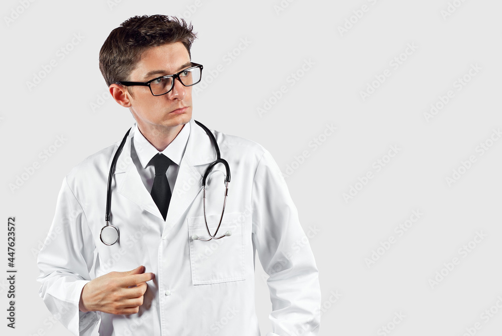 Doctor with a stethoscope on a white background. A man in a medical gown with glasses. A doctor with a pensive expression on his face. Doctor with a stethoscope on a white background. A man in a medical gown with glasses. A doctor with a pensive expression on his face.