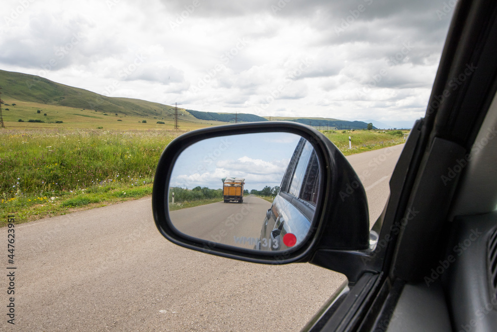 Car mirror and highway view, black car and nature landscape Car mirror and highway view, black car and nature landscape