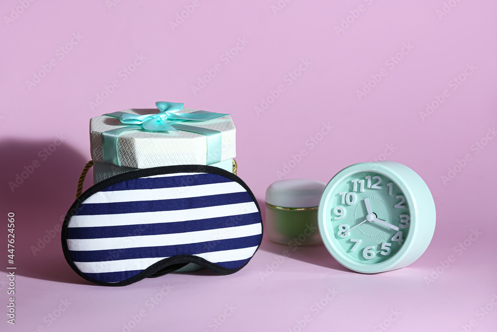 Stylish sleeping mask, clock and gift box on color background Stylish sleeping mask, clock and gift box on color background