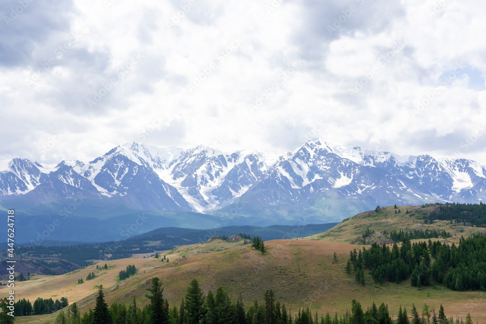 snowy peaks of mountains and steppe on a background of cloudy sky snowy peaks of mountains and steppe on a background of cloudy sky