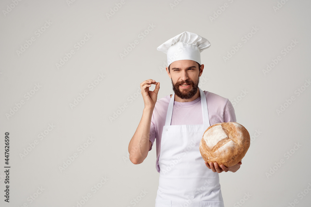 bearded man in a white apron with bread in his hands baking light background bearded man in a white apron with bread in his hands baking light background