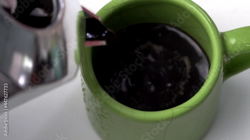 Close up hand pouring black coffee in green ceramic glass