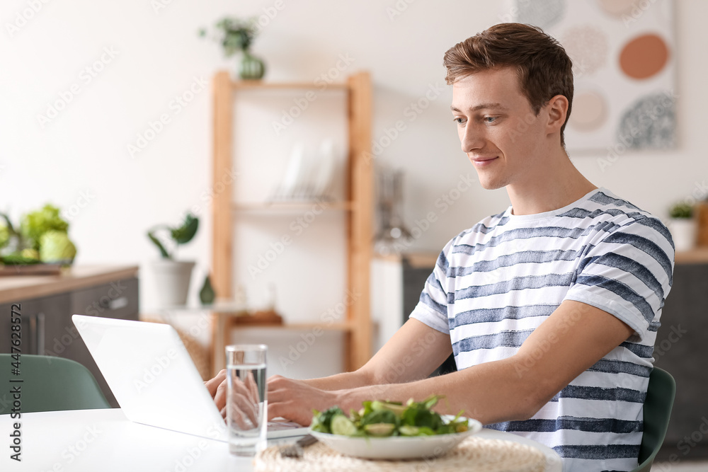 Young man using laptop while cooking in kitchen Young man using laptop while cooking in kitchen