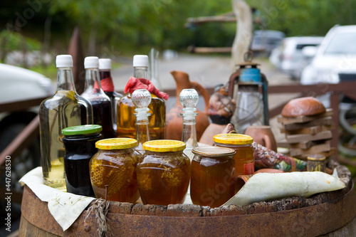Jars of honey and honeycomb are on a barrel for sale.