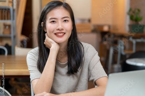 smiley asian young woman sitting in the cafe.