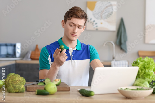 Young man using laptop whil...