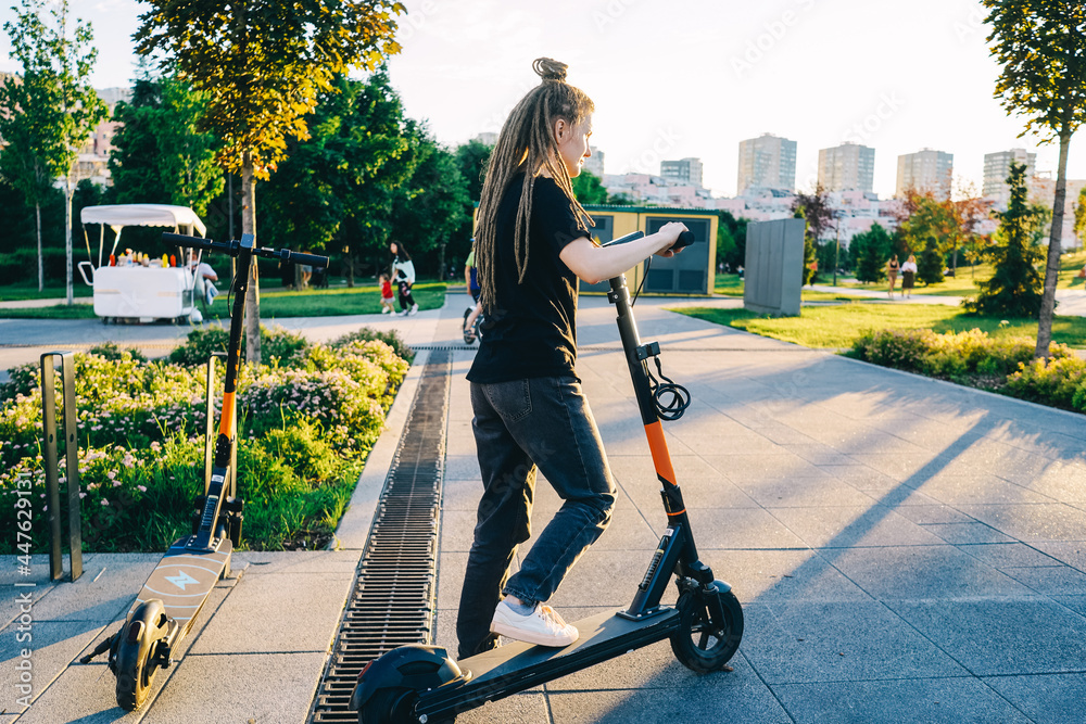 Woman rent an electric scooter in park. Woman rent an electric scooter in park.