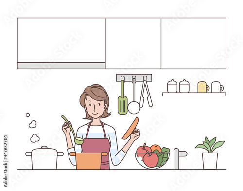 キッチンで料理をするエプロン姿の若い女性