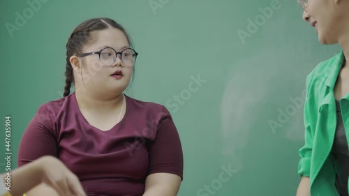 Autistic Asian girl sit in classroom with teacher and friend to do learning. young are happy doing activities to enhance knowledge skills. confidence to live together. Concept assertive photo