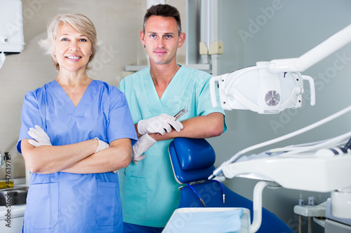 Portrait of smiling dentists standing in modern medical office