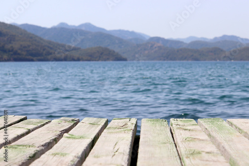 Beach vacation on the sea, background for summer holidays and travel. View from old wooden pier to deep blue water and misty mountains covered with forest