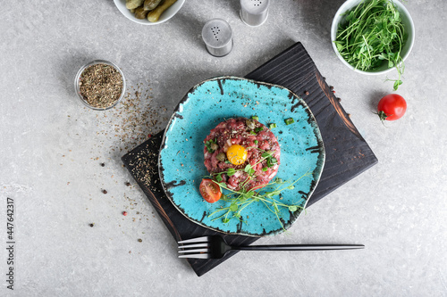 Plate with tasty beef tartare on grunge background