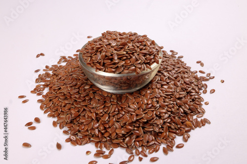 Flex seed flaxseed in small glass bowl over pile on white background