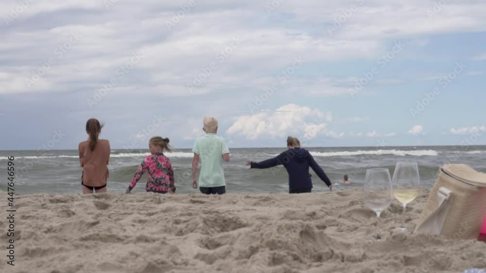 Children look at the turbulent sea in the waves in the summer on the beach, the view from the back. Children look at the turbulent sea in the waves in the summer on the beach, the view from the back.