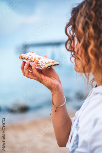 A young girl eating a coca de San Juan on the beach, a typical meal to celebrate San Juan night the summer solstice