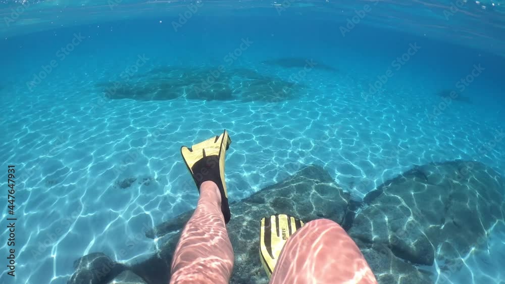 Punta Molentis, Sardinia, Italy. 30-06-2021. 
Young man swimming in clear sea water while wearing Mares fins.
Mares avanti quattro flippers yellow colored. 