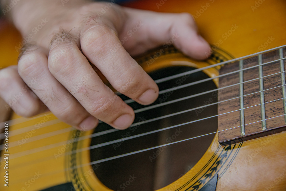 Fototapeta premium close-up of a guitar playing with a man's hand playing the strings