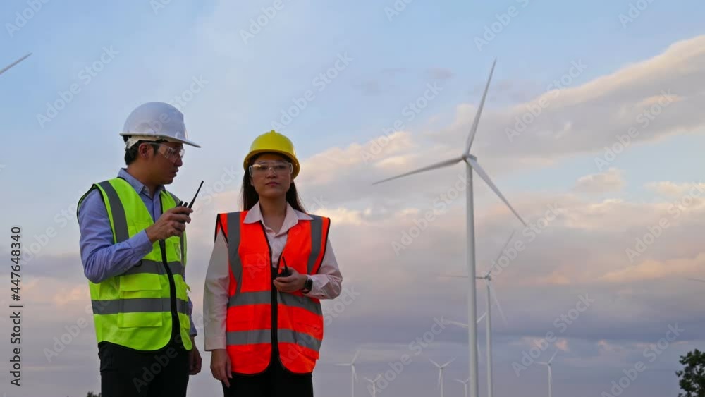 Young engineer team using walkie-talkie to checking system against wind turbine farm. Young engineer team using walkie-talkie to checking system against wind turbine farm.