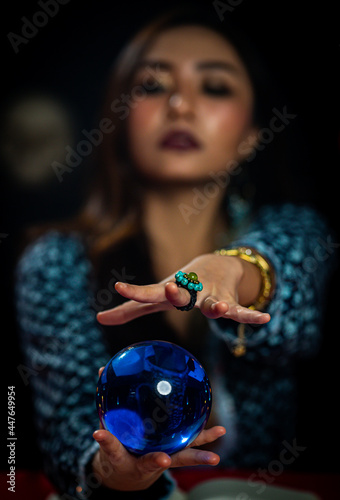 Blurred Asian witch telling fortune by crystal ball