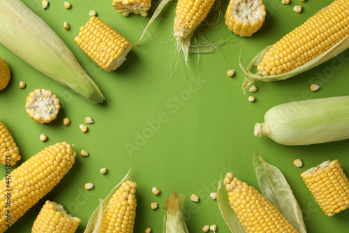 Fresh raw corn on green background, top view