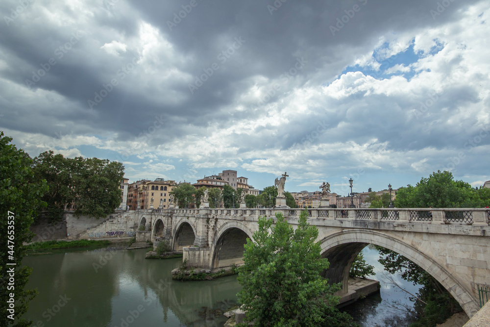 Panoramic of St. Angelo Bridge on cloudy day in summer 2021 Italy.Pedestrian bridge, built in 134 A.D., with travertine marble fascias and spanning the River Tiber.