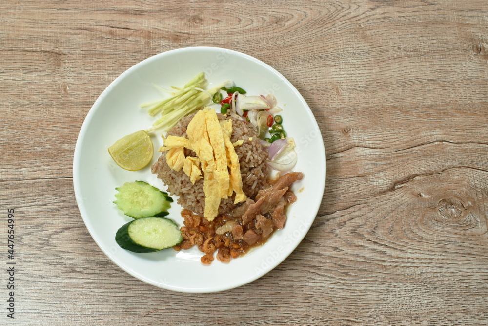 rice mixed with shrimp paste topping slice Thai egg omelette couple sweet pork in gravy and vegetable on plate rice mixed with shrimp paste topping slice Thai egg omelette couple sweet pork in gravy and vegetable on plate