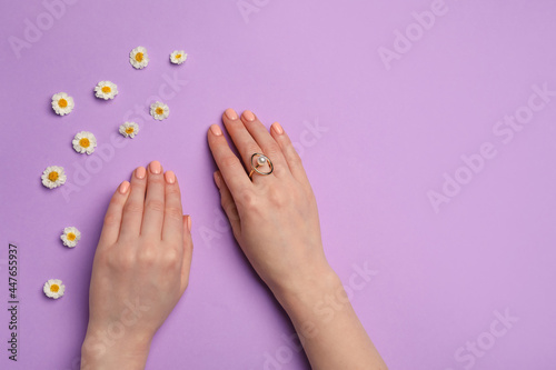 Hands with beautiful manicure and flowers on color background