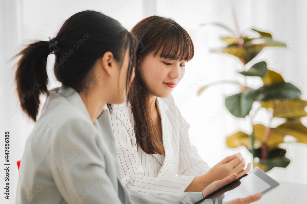 Businesswoman discussing charts and graphs showing on tablet screen with friend with smiling faces in the meeting room. Brainstorming and teamwork concept. Businesswoman discussing charts and graphs showing on tablet screen with friend with smiling faces in the meeting room. Brainstorming and teamwork concept.