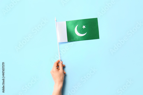 Female hand with Pakistan flag on color background