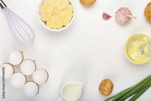 Frame made of ingredients for tasty potato casserole on light background