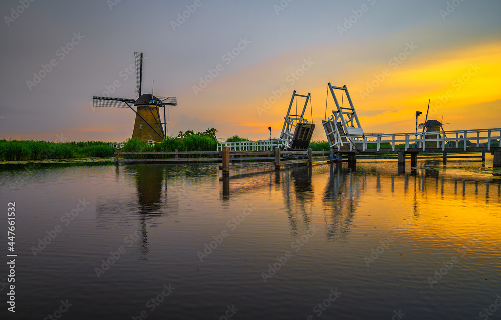 Obraz premium Sunset above a historic drawbridge and old windmills in Kinderdijk, Netherlands