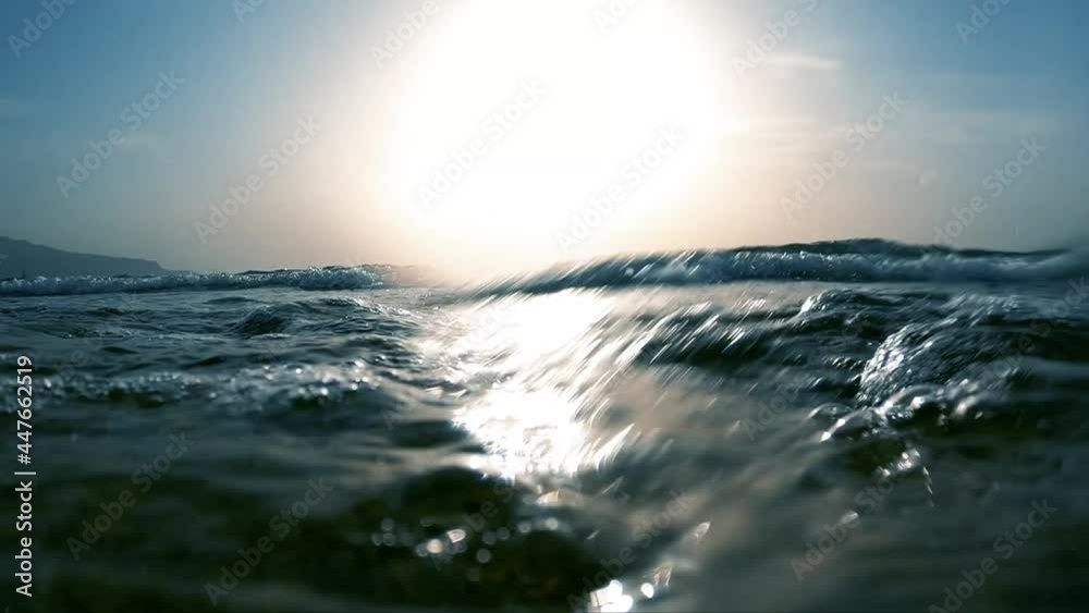 Slow motion of backlit sea waves crashing on the beach.  Camera partially under water pointing to the open waters, with audio