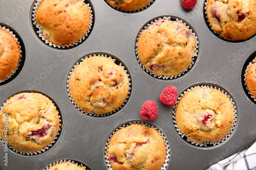 Baking tin with tasty raspberry muffins, closeup