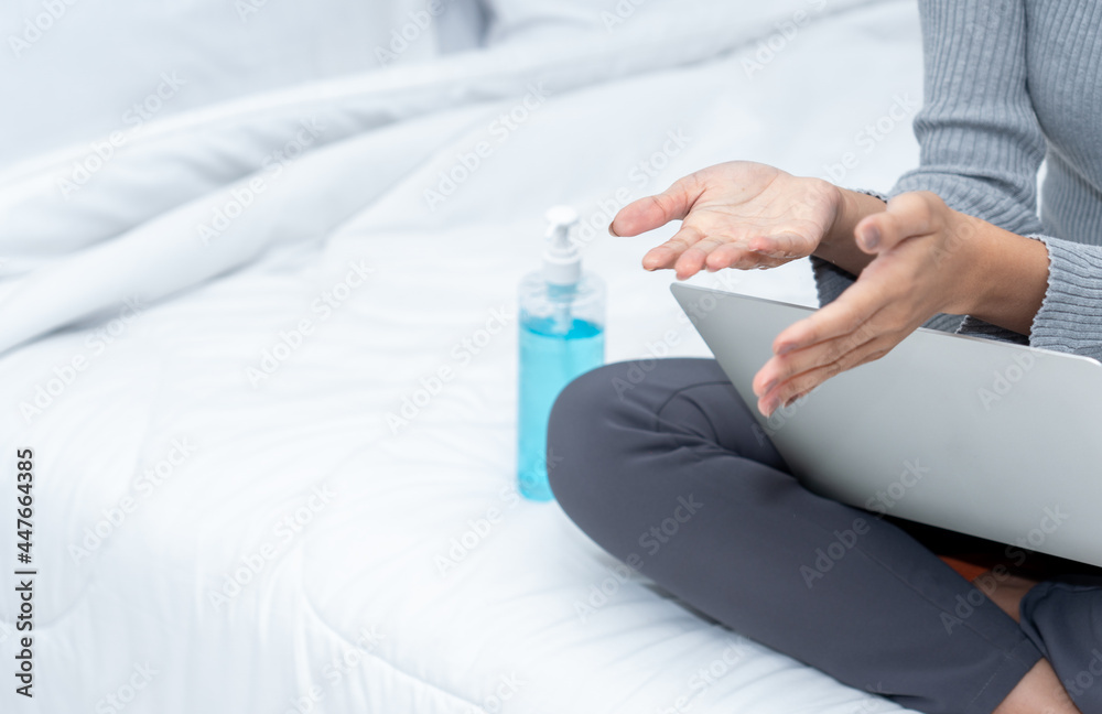 Fototapeta premium Close up picture of an Asian woman cleaning her hand with alcohol gel while working from home in quarantine
