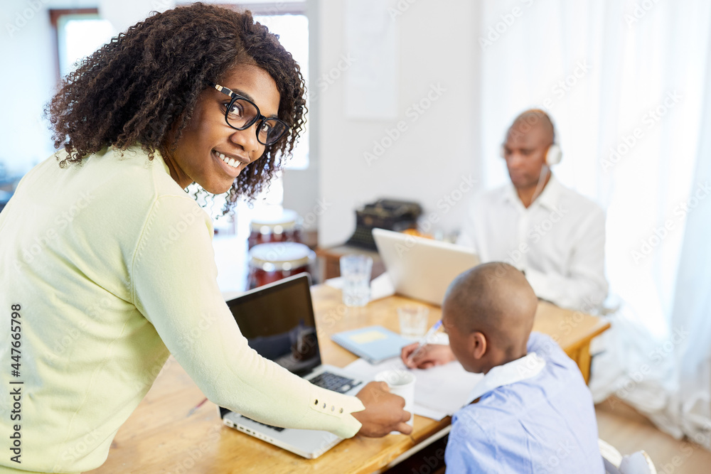 Afrikanische Frau kümmert sich um Sohn beim Homeschooling Afrikanische Frau kümmert sich um Sohn beim Homeschooling