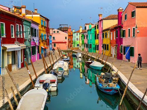 Boats docking and colorful houses in a canal street houses on Burano island, Venice, One unrecognizable people on the background.
