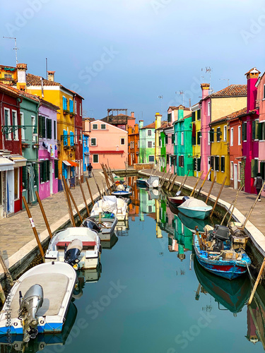 Boats docking and colorful houses in a canal street houses on Burano island, Venice, One unrecognizable people on the background. © Eric Isselée