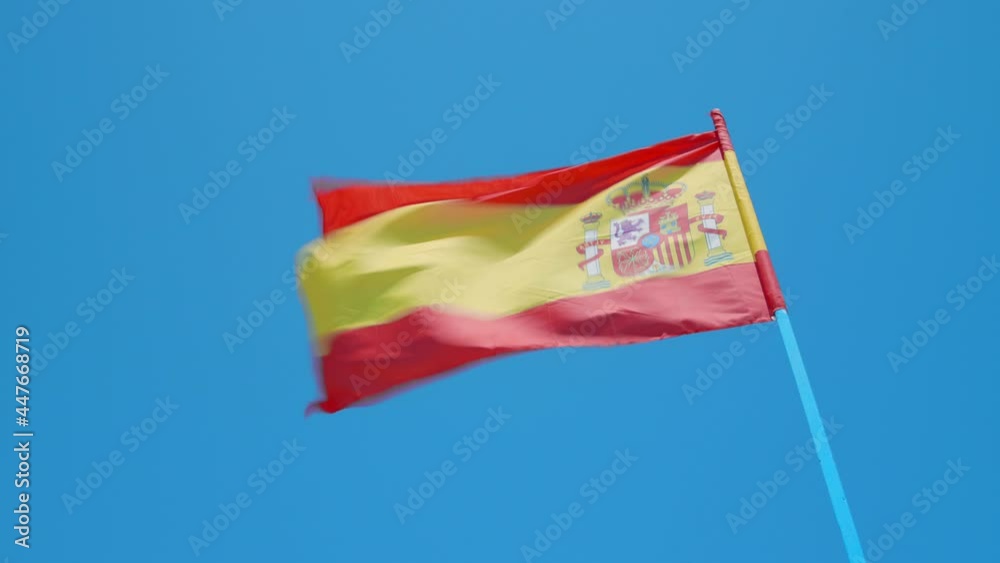 Spanish Flag Blowing In The Wind With Clouds And Blues Sky In The Background. - wide Spanish Flag Blowing In The Wind With Clouds And Blues Sky In The Background. - wide