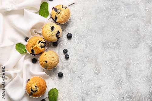 Tasty blueberry muffins on light background