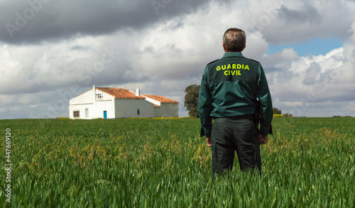 A Spanish civil guard watches over a country house from a grassy field. photo