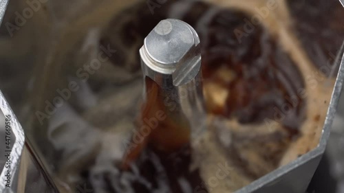 Close up macro shooting video of brewing coffee in a moka pot, fresh coffee and creama in the pot.