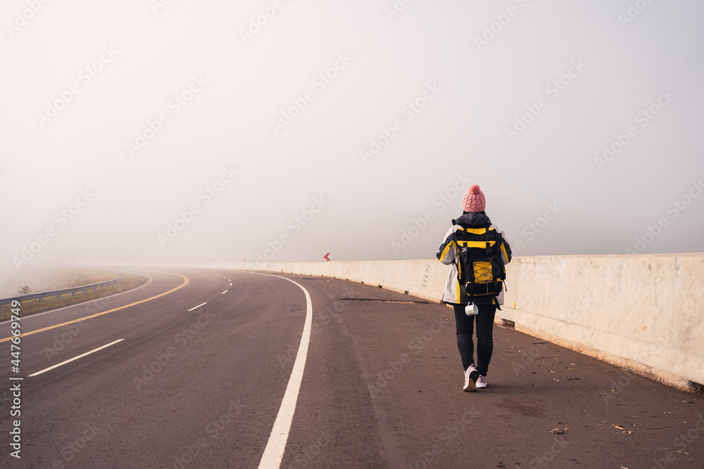 Obraz premium Image of a female hiker walking along an asphalt road .