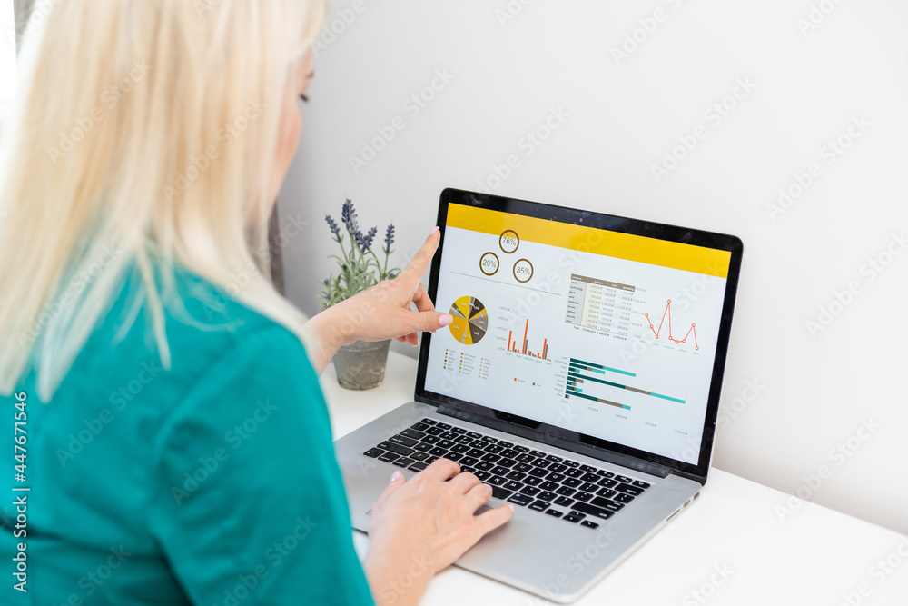 Fototapeta premium businesswoman analyzing statistics on laptop screen, working with financial graphs charts online, using business software for data analysis and project management concept, rear close up view