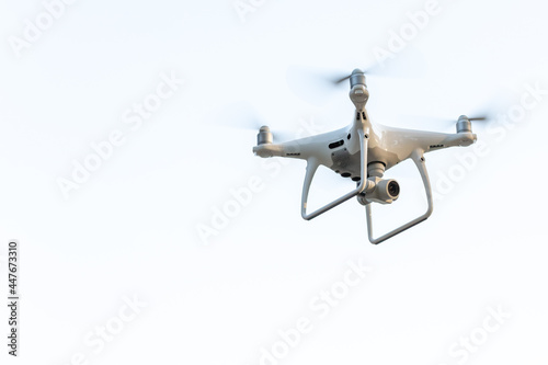 An unmanned aerial vehicle with rotating propellers on a light background. Space for the text.