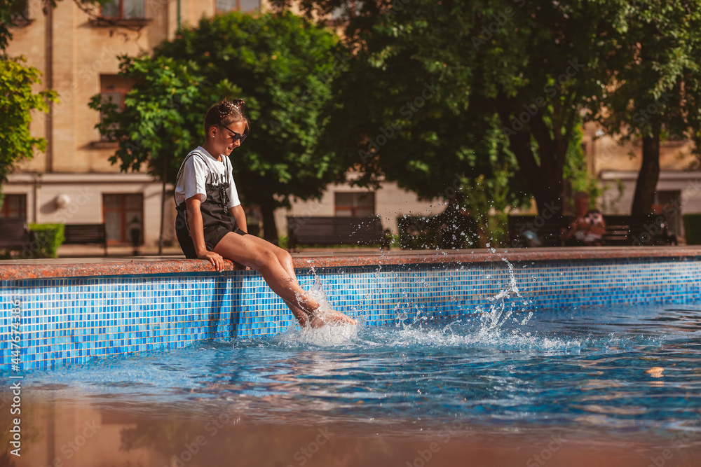 a girl is sitting by the pool in sunglasses and splashing water 