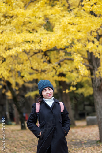 Happy woman enjoy at the park outdoor in Autumn season, Asian traveler in coat and hat against Yellow Ginkgo Leaves background © Jo Panuwat D