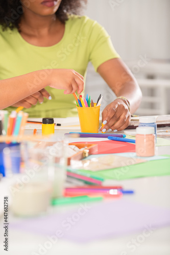 Close-up view of a teacher drawing in art class and the various colored pencils and school supplies on the table