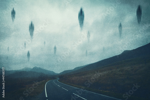 A spooky supernatural concept. Of spirits floating above a road in the mountains at night. With a grunge, textured edit.